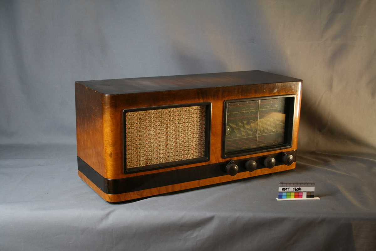 Brun rektangulær radio. Forside: skala med fire funksjons- og søkeknapper. Indikator for signalstyrken på stasjonen, kalt "trolløye". (Jo sterkere stasjonen er, desto større blir "øyet". Dette skjer ved hjelp av et elektronisk fluoriserende belegg.) Høyttaler med trekk av tekstil. Bakside: intakt bakplate med uttak for antenne, grammofon, jord, strøm, ekstrahøyttaler, styrkekontroll og apparathøyttaler.