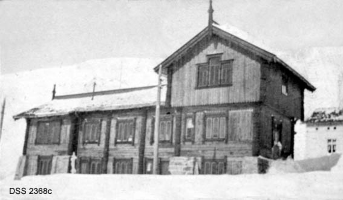 Haukeliseter fjellstue.  Seks vinteropptak, antakelig fra tida like før 1900.  A. Våningshus i djupsnø, en panelt og kvitmalt bygning til høgre, en uthusbygning og et våningshus i drakestil til venstre for dette.  B.  Uthus og våningshus i drakestil, mann med hund foran drakestilhuset.  C.  Våningshus med drakestilpreg, der særlig en toetasjes fløy til høyre i bildet har lånt trekk fra stabbur og loft i Telemark og Numedal.  D. Panelt og kvitmalt våningshus i en etasje, men med rom på loftet.  Snøen står om lag midt på veggen på forsida av huset, nestet opp til raftet på baksida.  En mann bærer noe mot inngangen.  E.  Bryggerhusliknende bygning med torvtak.  En mann ved langveggen og en i døra.  F.  11 personer foran inngangen til den kvite bygningen på fjellstua. Reinsdyrgevir over døra. 