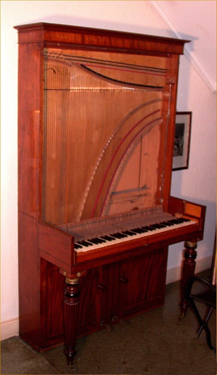 Instrument med omfang: FF - f'''' (6 oktaver).

Firkantet korpus med to bein framme og en rød tekstilavdekking på forsiden. Finer sannsynligvis mahagoni. Lokk tredelt med to knapper og mørk treinnlegg. Når lokket åpnes kan to halvsirkelformede plater felles frem som hyller for lysestaker.
Under klaviatur to dører foran klangbunnen.