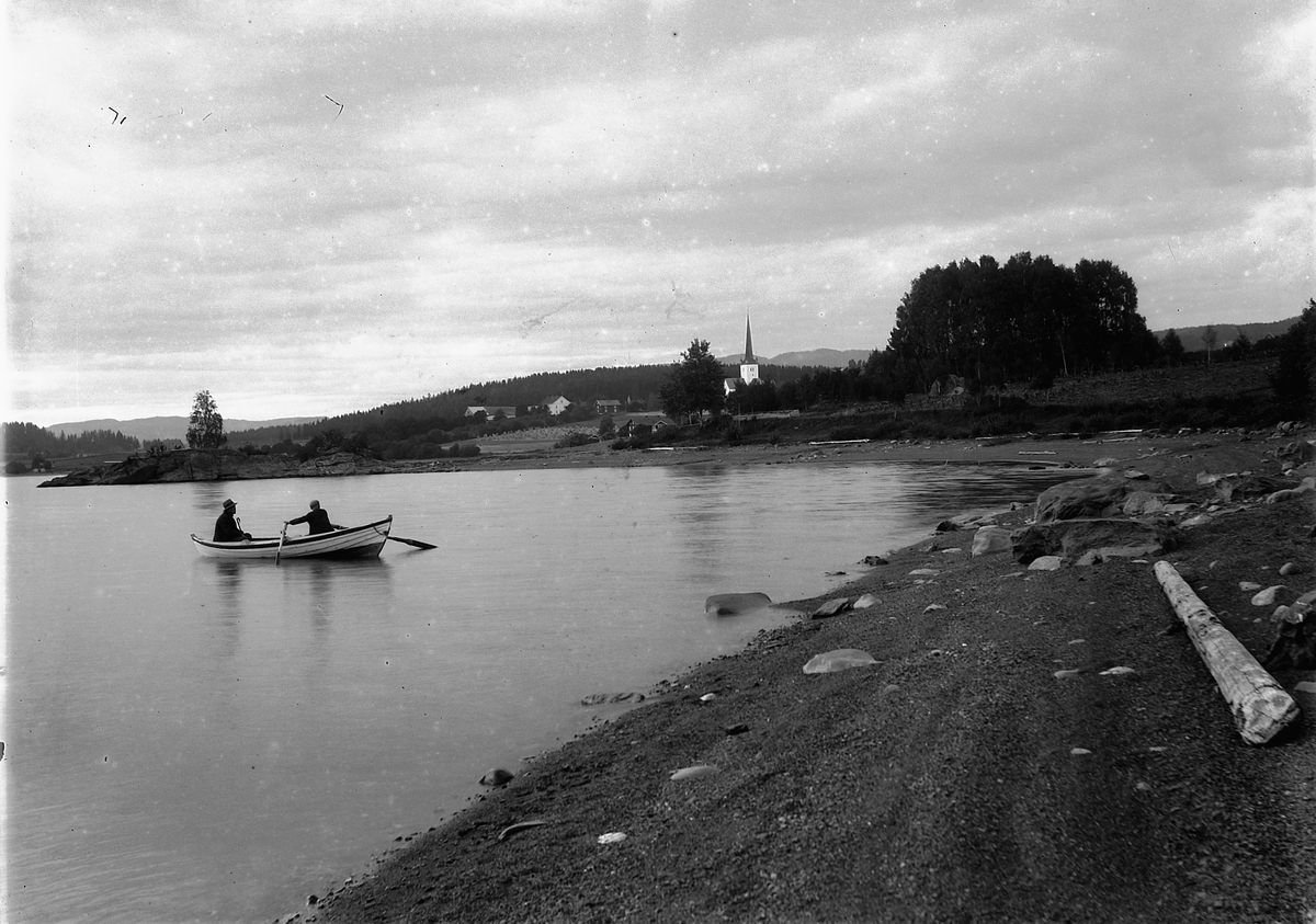 Ringsaker, 2 menn i robåt på Mjøsa, Ringsaker kirke med prestegården i bakgrunnen, Hammerlundsberget stikker ut i Mjøsa,