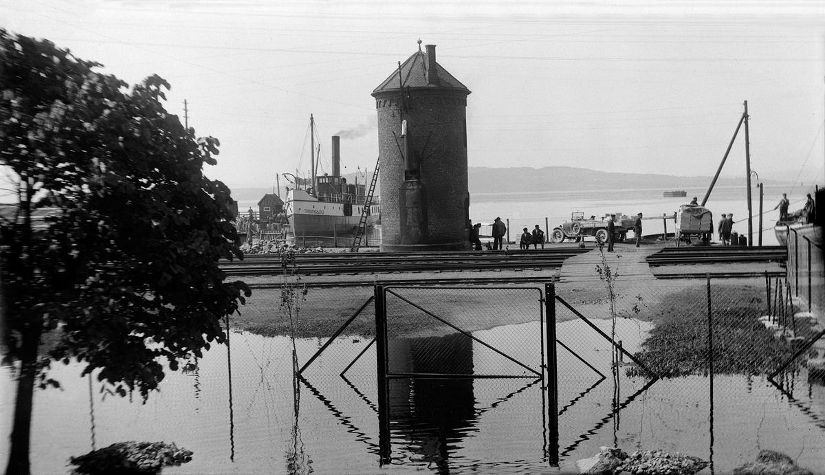 Hamar jernbanestasjon, Vanntårnet, mjøsflommen 1927, mjøsbåten D/S Tordenskjold ligger ved Jernbanebrygga, lastebil fra Hagen transport, gangbro over jernbanskinnene,