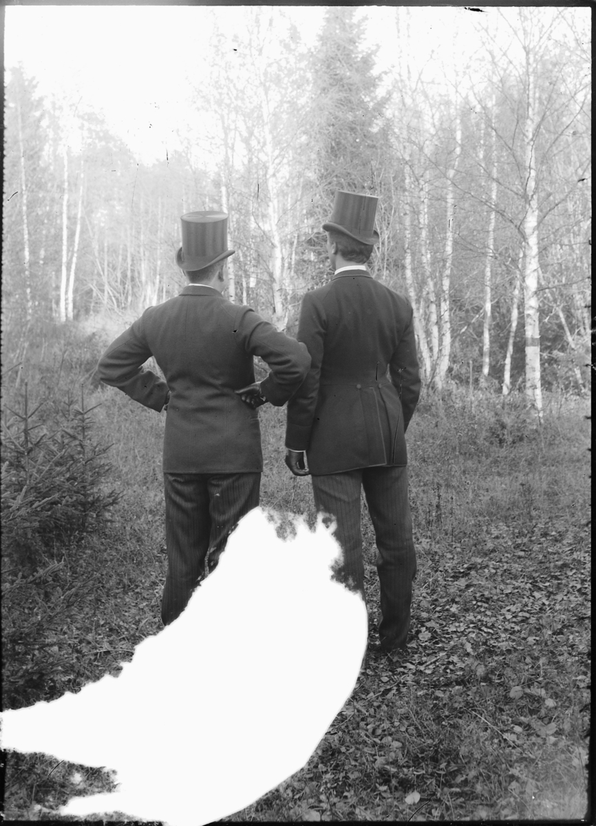 To menn med flosshatt i skogen. 