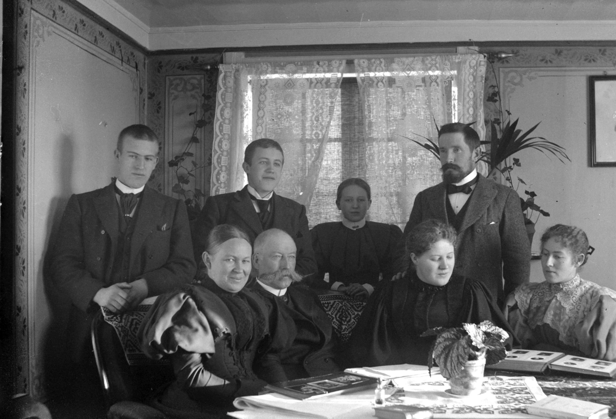 Ringsaker, Veldre, Løken østre, familiegruppe, foran fra venstre: Antonette Ring født Todderud (1854-1919), rittmester Paul Ring (1843-1909), Wilhelmine Løken (Mimi) (1876-1953), antatt: Antonette Barbara Ring (Lally) gift Skappel (1877-), bak fra venstre: Barthold Ring (1881-1951) Paul Ring (1879-1907), Antonette (Tulla) Ring (1883-) gift Hersaug og Ole Løken (1860-1924), interiør stue, ser på fotoalbum, 
Mimi, Lally, Tulla, Paul og Barthold er barn av Paul Ring og Antonette Ring