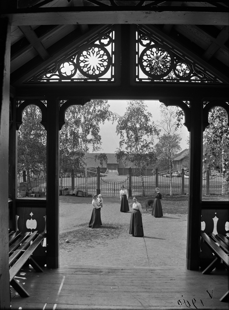 Hovinsholm gard, Helgøya, Ringsaker. Sveitserstil, veranda.  Ytre og indre gårdsplass sett fra inngangspartiet på hovedbygningen. Foto Jacob Hoel 1900.
Fra v.: Magda Eriksrud, siden gift Raknerud, med Jacob Hoel (1899-1998), Sigrid Pauline Hoel, moren Albertine Hoel (1842-1926) og frøken Styhr.