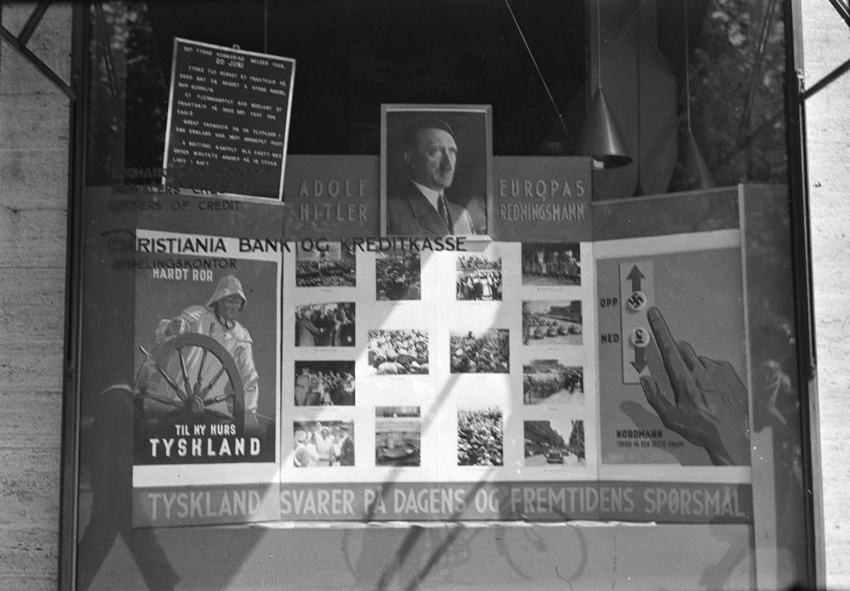 Oppslagtavle, utstilling i vindu til Christiania Bank og Kredittkasse. "Adolf Hitler Europas redningsmann. Tyskland svarer på dagens og morgendagens spørsmål" Nasisme. Propaganda.