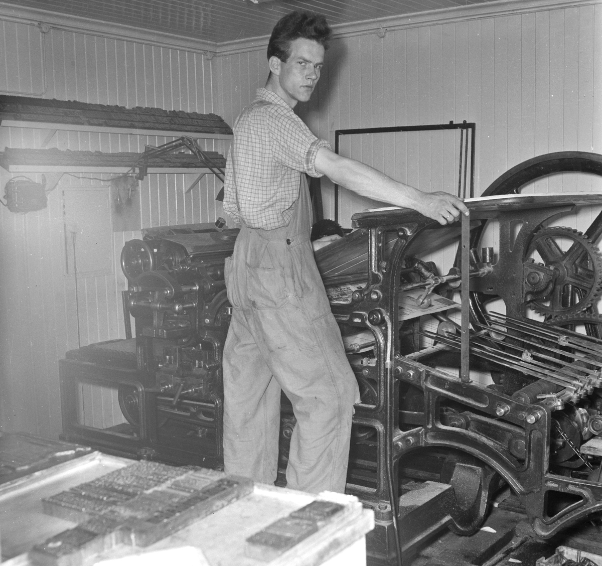 Ringsaker Blads trykkeri i Moelv. 1955. Kåre Karlsen ved den gamle flattrykkpressa. 