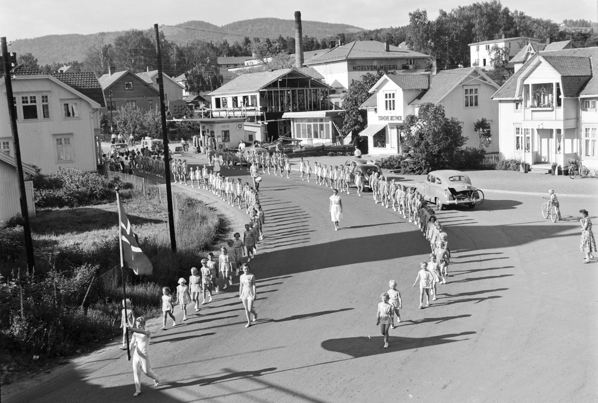 Turnstevne i Moelv i 1959. Turnerer marsjerer gjennom Storgata på veg til Idrettsparken. 