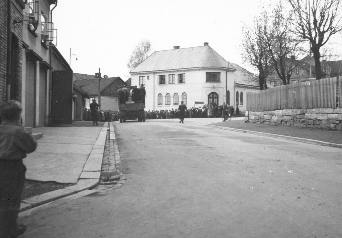 Hamar brannstasjon, 2. verdenskrig. "N. S fanger føres fra brannvakta i Hamar til Hamar kretsfengsel i lastebil med bevæpnete vakter 10. mai 1945" Fredsdagene 1945.