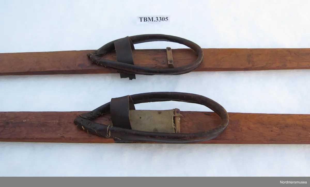Ski med tuppar og binding av lær. Øyrene er skrudde og spikra fast i sidene på skia. Hælreimene er av spanskrøyr kledd med skinn.
Det kan vere ski frå to ulike skipar.
Ved tåbindinge, uner skisolen, har det vore festa eit underlag av strie.