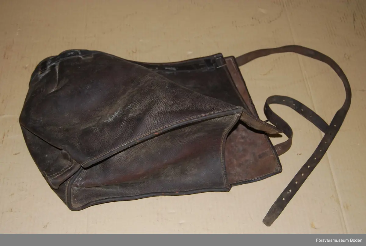 Mörkbrunt läder med ett utskjutande "horn". Ena gaveln öppen. Troligen till pjäs.