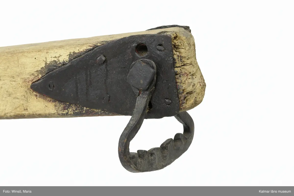 KLM 12823. Plog, trä, metall. Plog med handtag och ås av trä. På åsens ena sida sitter en rist av järn fastskruvad. Längst ut på åsen en dragkrok av järn för anspänning av dragdjur. Plogblad med bill av järn. Träkil mellan plogblad och landsida. Plogen är järnskodd på undersidan. Den har även varit järnskodd på landsidan men denna saknas. Spikarna sitter kvar i träet. Fyra slåar mellan handtagen, två av järn och två av trä. Det nedersta är fastskruvat i plogbladet. Plogen är svartmålad med en röd eventuell rostskyddsfärg under. Målad under senare tid.