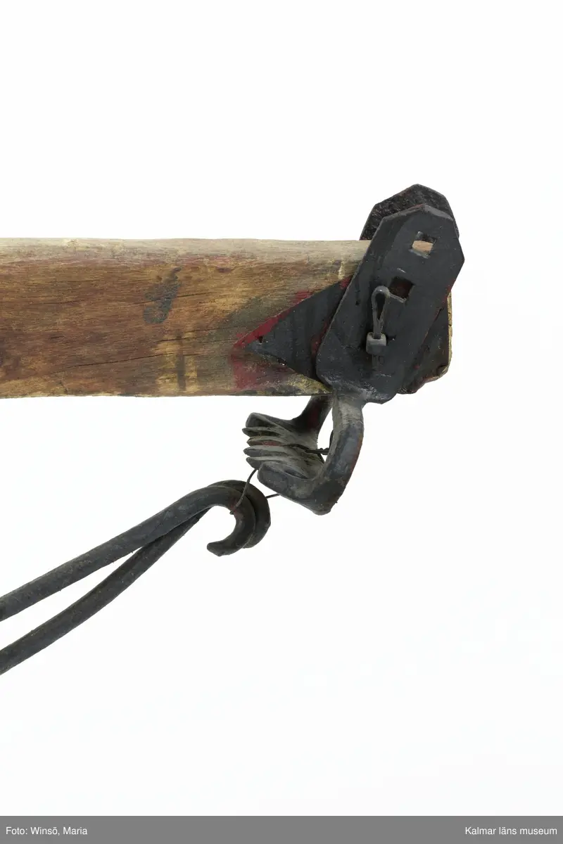 KLM 12824. Plog, trä, metall. Plog med handtag och ås av trä. Landsida av trä, järnskodd. Vändskiva och bill av järn. Tvärslå av järn mellan handtag och ås. Slåar mellan handtagen, två rundformade av järn, en U-formad av järn, en kantig av järn och en av trä. Längst fram på åsen en dragkrok av järn med reglage för inställning av höjd. På åsens mitt en fastskruvad rist. Risten är sammanfogad, eventuellt med färg, med billen. Tre långa krokar av järn hänger under åsen och möts i en järnring. Plogen är trasig på landsidan, träet är sprucket och järnbeslaget har lossnat. Plogen är rödmålad men färgen är kraftigt avskavd. Plogens järndetaljer är svartmålade med en röd eventuell rostskyddsfärg under. Den svarta färgen och rostskyddsfärgen är målad senare.