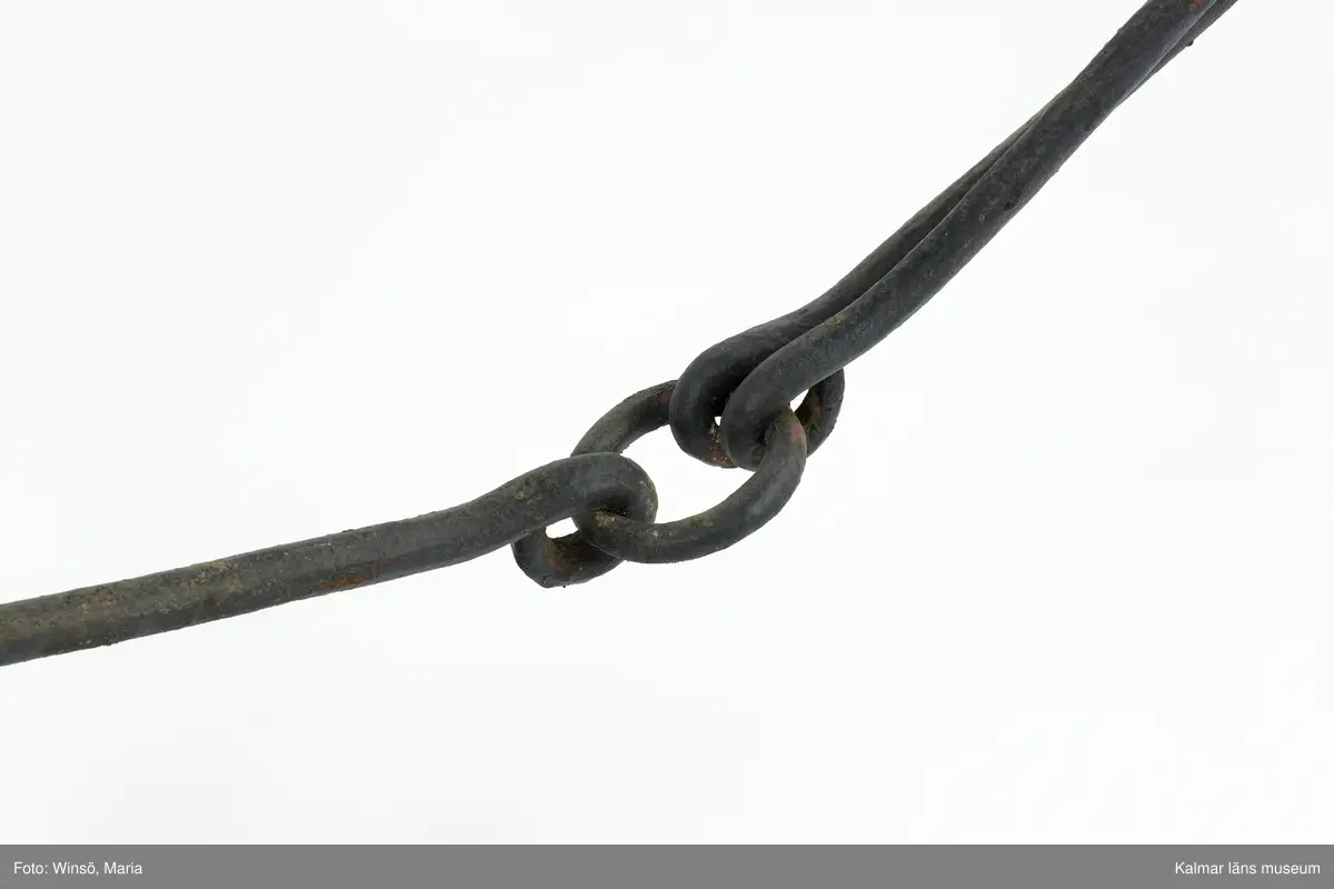 KLM 12824. Plog, trä, metall. Plog med handtag och ås av trä. Landsida av trä, järnskodd. Vändskiva och bill av järn. Tvärslå av järn mellan handtag och ås. Slåar mellan handtagen, två rundformade av järn, en U-formad av järn, en kantig av järn och en av trä. Längst fram på åsen en dragkrok av järn med reglage för inställning av höjd. På åsens mitt en fastskruvad rist. Risten är sammanfogad, eventuellt med färg, med billen. Tre långa krokar av järn hänger under åsen och möts i en järnring. Plogen är trasig på landsidan, träet är sprucket och järnbeslaget har lossnat. Plogen är rödmålad men färgen är kraftigt avskavd. Plogens järndetaljer är svartmålade med en röd eventuell rostskyddsfärg under. Den svarta färgen och rostskyddsfärgen är målad senare.