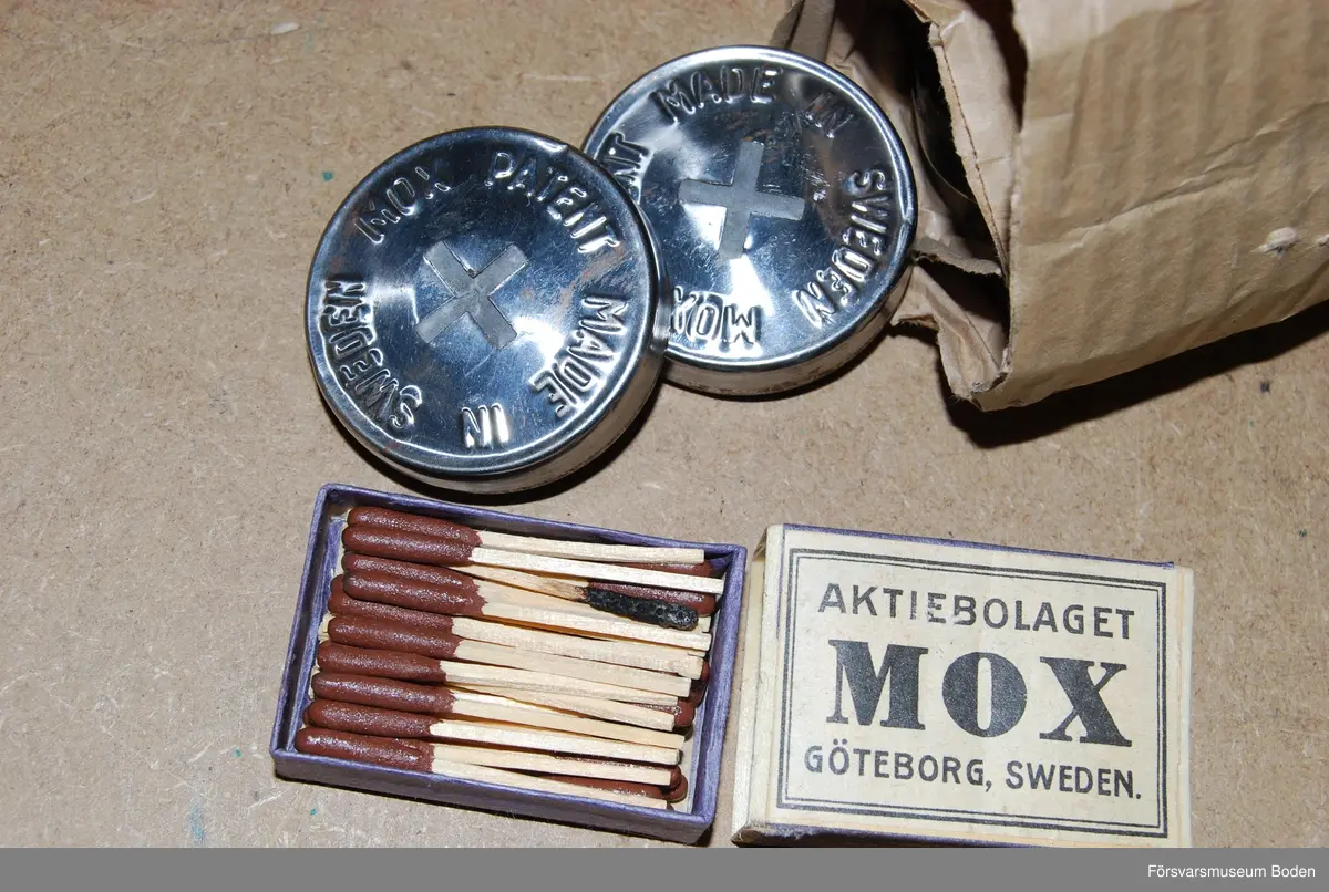 Kopparhuvud med behållare för dosa vars innehåll avger värme vid antändning. Behållarens lock kan låsas med skjutbar mässingsring på handtaget. Ett antal bränsledosor förpackade i wellpapprulle medföljer, samt stormtändstickor med firmanamn.