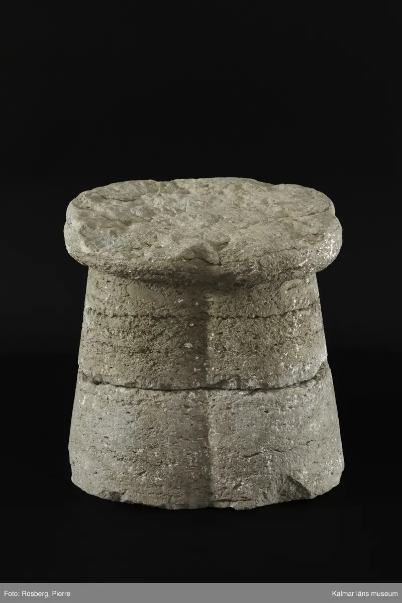 KLM 35218:2:1-2. Dopfuntsfot, av kalksten, 2 delar. Mått, hela foten: höjd 40 cm, största bredd 43 cm. Foten sammansatt av fyra halvkolonner, konade med fyrklöverformad vulst upptill. Saknar fotplatta. Foten som är det enda som återstår av funten är eroderad efter lång tid utomhus. Den har en liten skada vid skarven och en horisontell spricka.