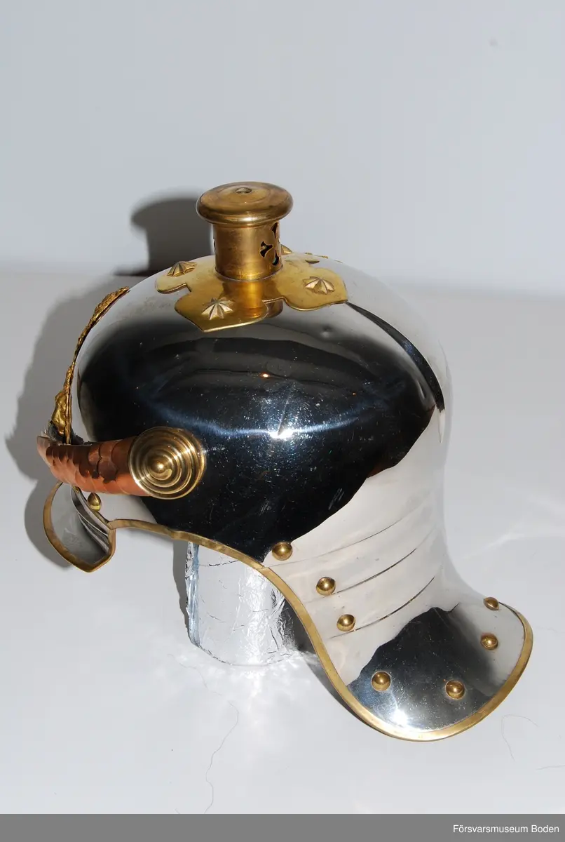 Förnicklad stålplåt med förgyllda beslag. Bl.a. förlängt nackstycke jämfört med tidigare m/1879. Upptill skruvfäste för plym m/1887 av vitt tagel (vid stor paraddräkt) eller pik, båda medföljer. Gul sidenkokard under hakremsknappen på höger sida. Framtill förgylld vapenplåt med blå emalj.