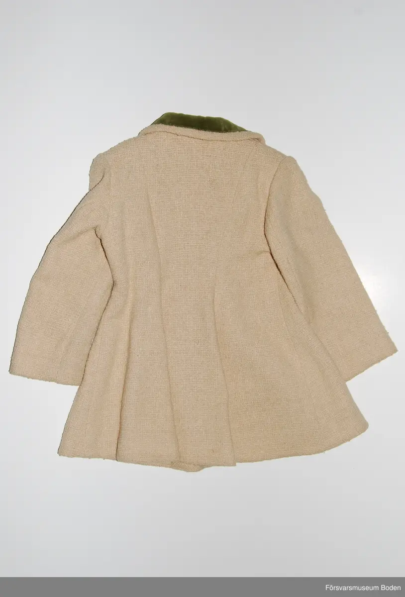 Beige textil med knappar och kragfoder av grön plysch. Kappans foder av senapsgult sidentyg. Ej fabrikstillverknad, saknar märkning.