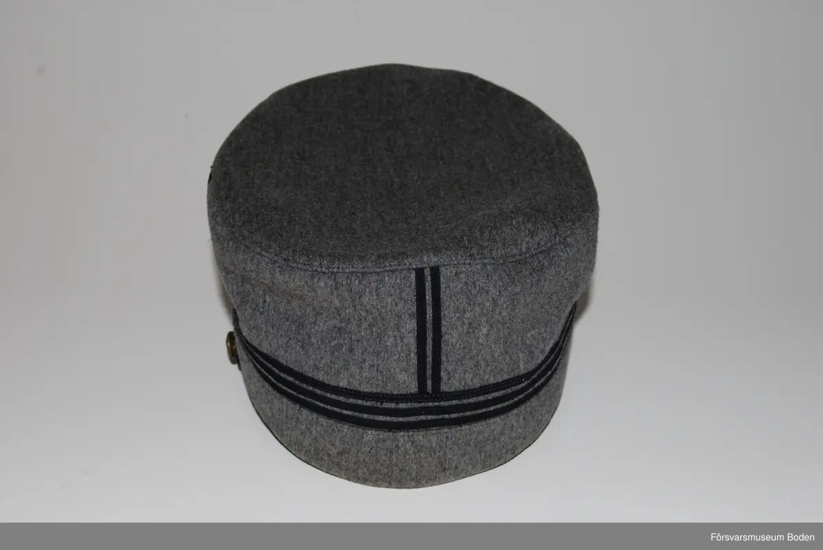 Ljusgrått kläde med tre smala band av blått kläde runt mössan betecknande kapten. Framtill mössmärke m/1865 i blå emalj samt upptill landstormsmärke m/1926 med gult broderat kors på blått kläde. Mössremmen fäst på sidorna med landstormens knapp modell mindre. Buren av fil. dr Arvid Moberg.