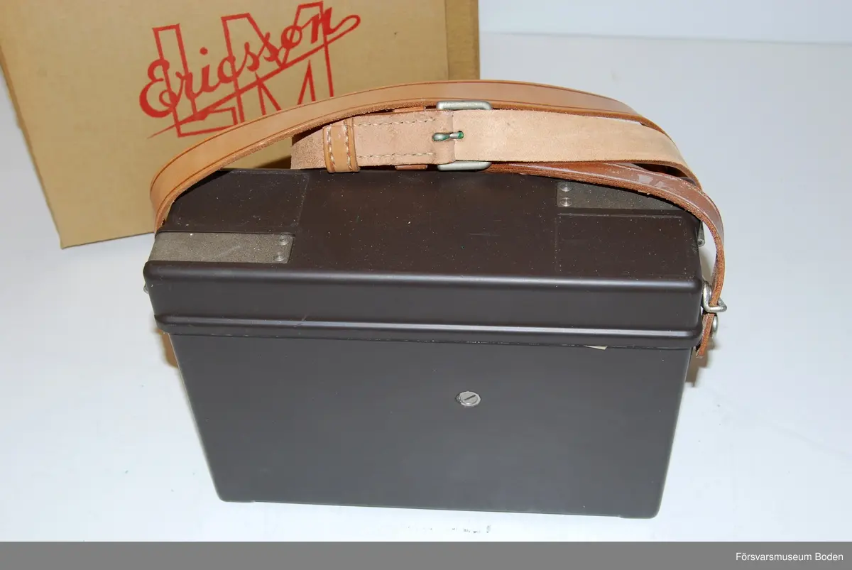 Ny i öppnad kartong. Telefonapparat m/1937 utan LB/CB-omkopplare och klyka.  Tillverkad under vecka 50 1963 enligt stämplar på chassi och emballage. Inget synligt serienummer i övrigt.
