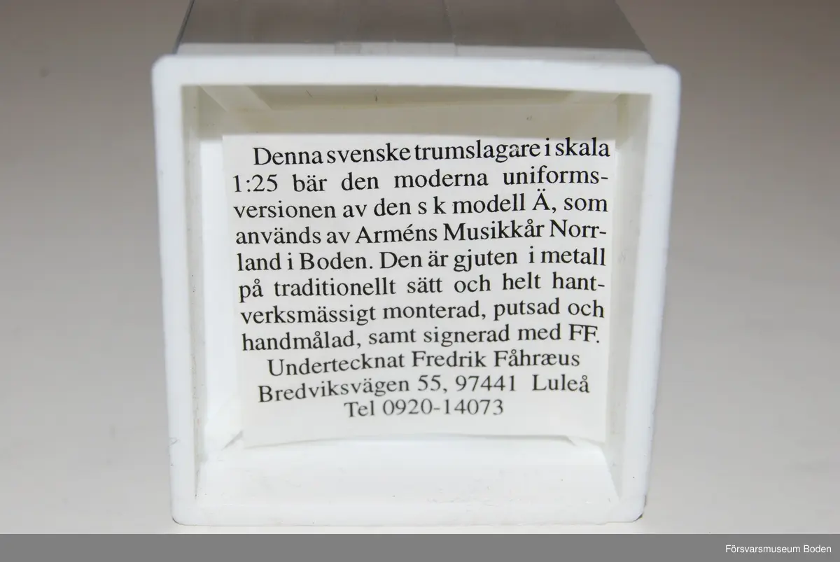 Gjuten och handmålad figur i skala 1:25. Förebilden är en trumslagare vid Arméns musikkår Norrland, Boden. Den pålimmade trumman har lossnat.