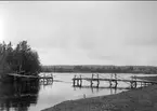 Del av bron bortsprängd, Boden omkring år 1900. Objektkommentar: Ingår i en serie bilder som visar hur en mindre bro först snvändes sedan delvis sprängts och verkan av sprängningen.Senare än år 1900.Det är en ingengörtrupp som utför sprängningen och sådant förband  började utbildas först 1902 (i Notviken intill Norrbottens regementes övningsplats).