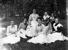 Gruppfoto av sex damer sittande i gröngräset omkring sekelskiftet 1900