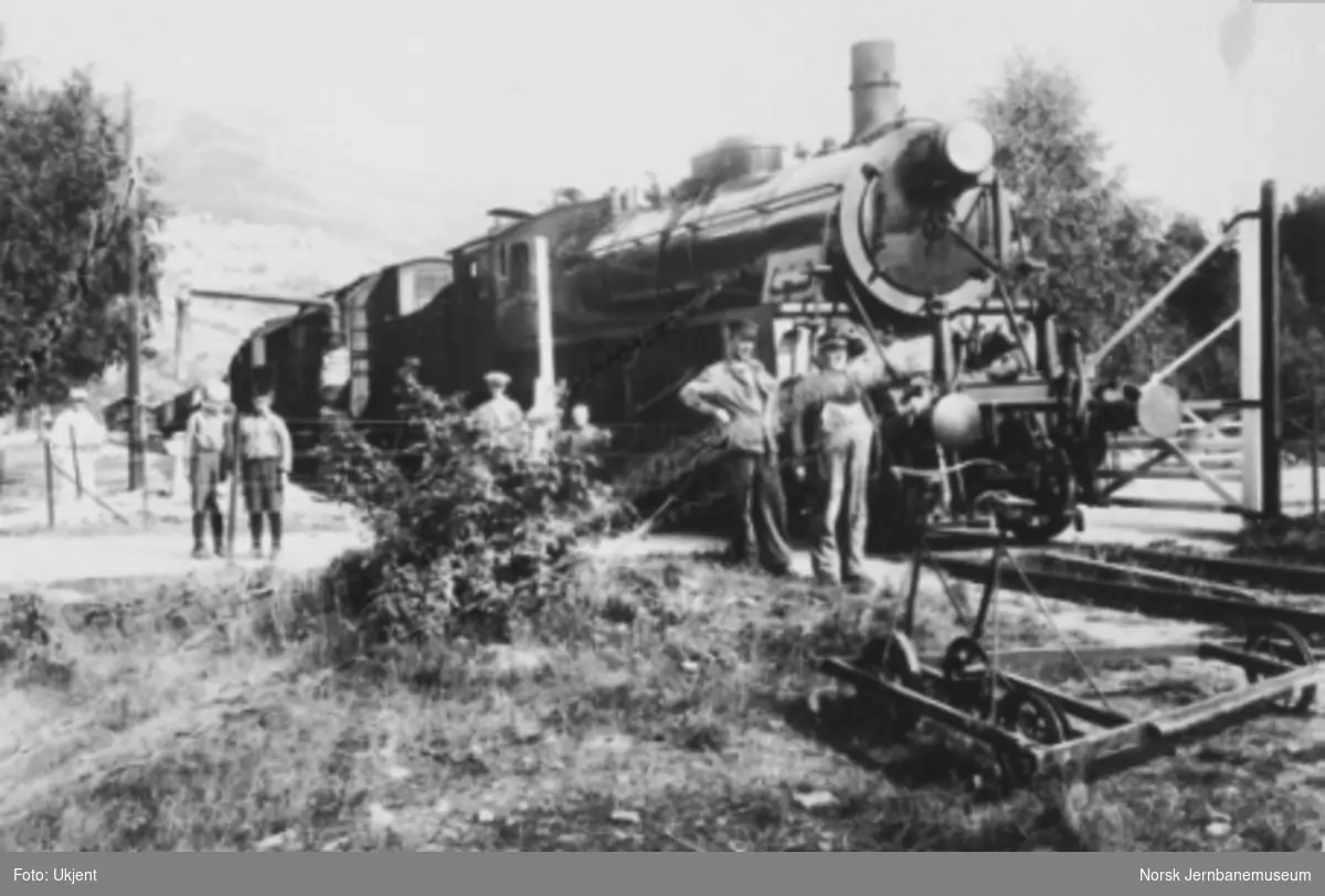 Damplokomotiv type 26c nr. 438 med godstog under oppholdet på Ringebu med lokpersonalet i forgrunnen