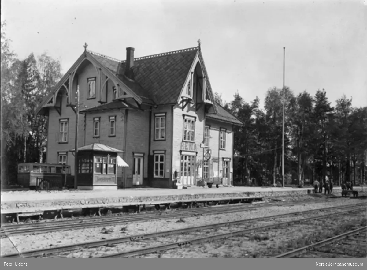 Rena stasjon med stasjonsbygningen, kiosken og en parkert buss med "Osen k..." på siden