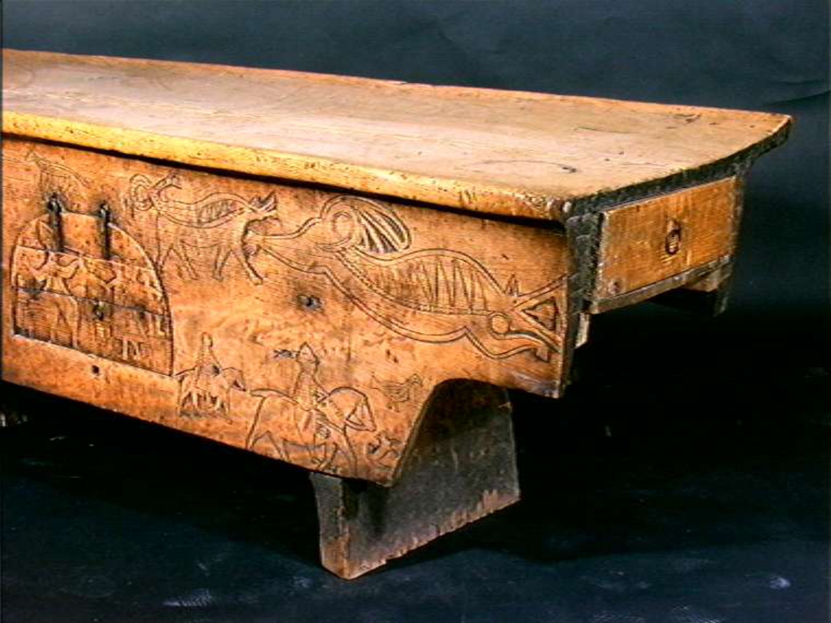 Bordplate og sider til bordet et laget av én tømmerstokk. Bendelene er skåret som formen til innsiden og sikret med dømlinger. Bordet har en frontside  med skurd og rispet dekor med middelalderspreg. Frontsiden har også en bueformet luke med hengsling nedtil. Undersiden er hvert dekket, så eneste inngang er fra luken. Bordet er ubehandlet.