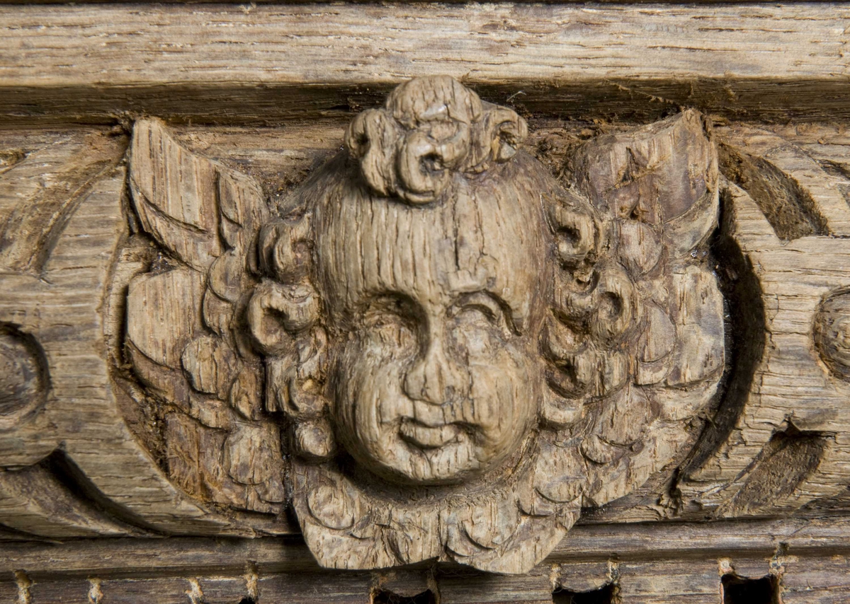 Rektangulært skap med skåret ornamentikk i flere deler. Øvre skap med to dører og gesims. Nedre skap med en klaff fremstilt som to dører. Skapdelene står på en sokkel med fire ben. Tympanon på øvre skap. Skapet ble opprinnelig brukt som skjenk med åpen klaff for å servere drikkevarer til gjester.
På overskapet i dørfyllinger er utskåret motiv fra gamle testament: "Samsons kamp med løven" og "Samson bærer bort Gazas byport". På underskap i fyllinger: "Samson slår filisterne med asenkjeven" og "Samson og Dalila". Dørene blir flankert av hermenpilaster. Mellom fyllinger på overskap aedikula med dyden "kjærlighet".  Som karyatide og atlant to utskårete figuerer "Adam og Eva" ved overskap. 
Klassiske profiler med eggstav, perlestav og tannsnitt. Beslagverkornament på skapsidene, gesimsens underside og profil på underskap. 
Utskårete hoder av løver, engler, kvinner, masker på gesimsens underside og profil på underskap. Sidebrett med hermer, portretter i medaljonger og beslagverk. Sokkelen består av dreide og utskårete ben, holdt av en ramme, Forsidens blending er dekorert med utskårete figurer og ornamenter i ørebruskstil.
Flere deler er sekundære.