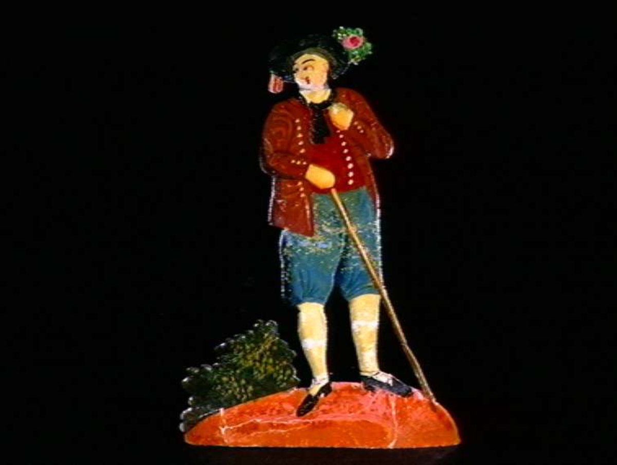 Figurer i papir med trefot i form av husfasader, tær, dyr og mennesker. Tilhørende eske.