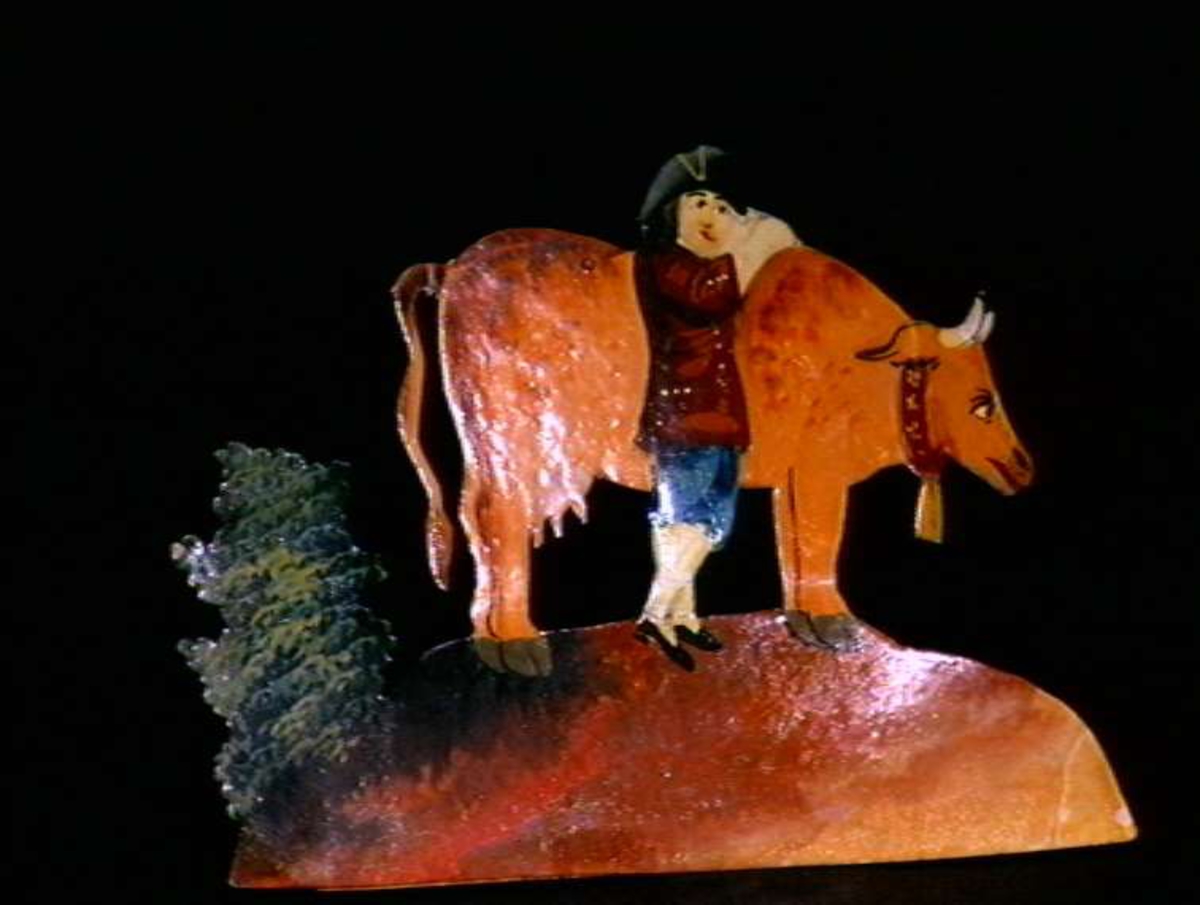 Figurer i papir med trefot i form av husfasader, tær, dyr og mennesker. Tilhørende eske.