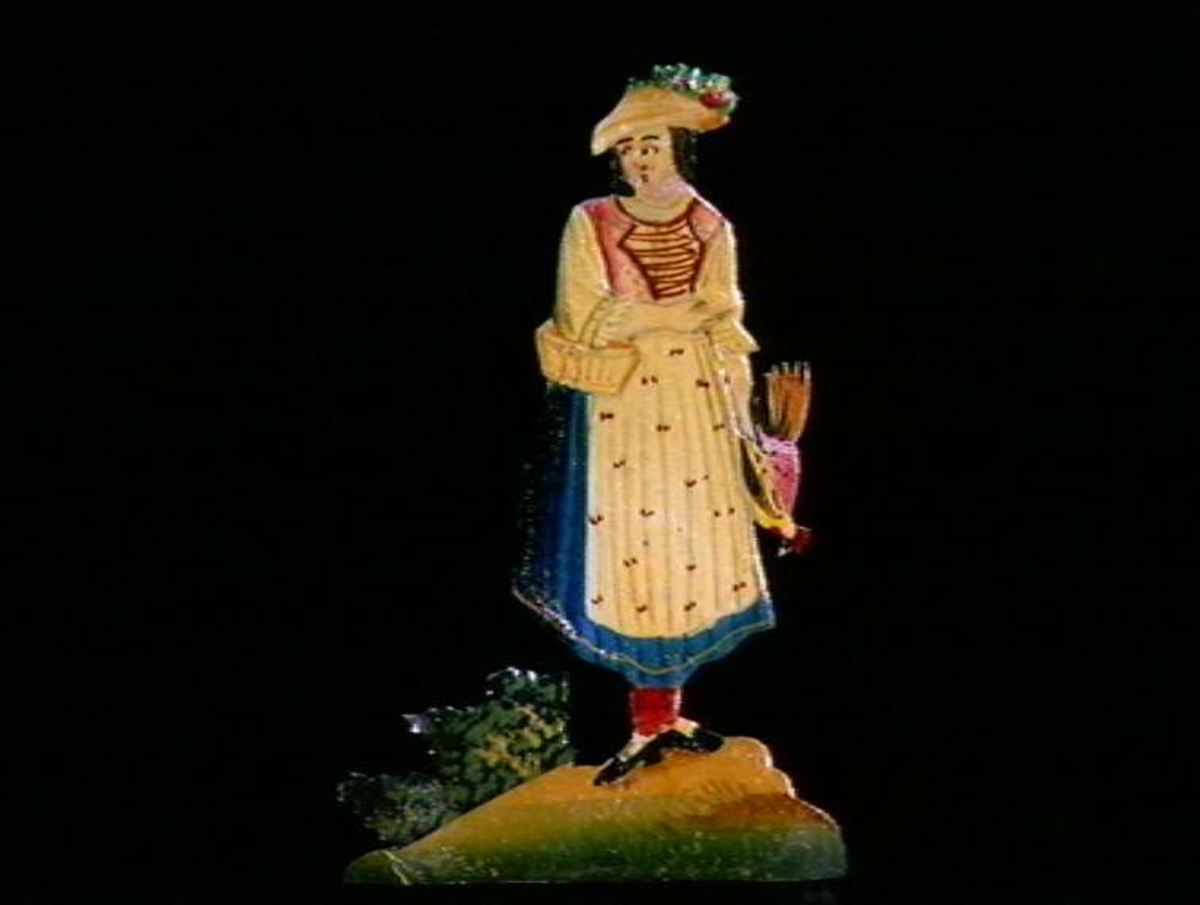 Figurer i papir med trefot i form av husfasader, tær, dyr og mennesker. Tilhørende eske.