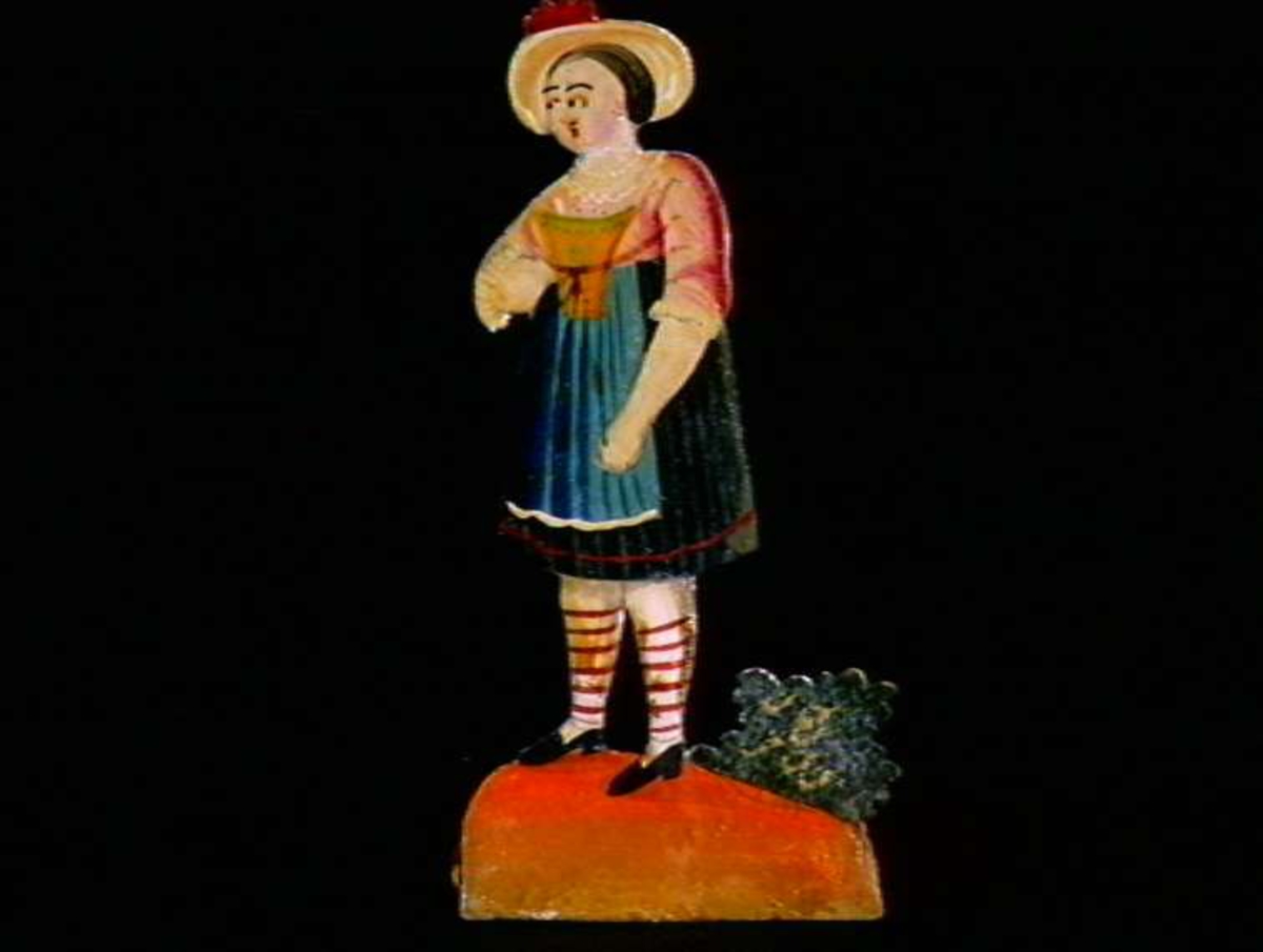 Figurer i papir med trefot i form av husfasader, tær, dyr og mennesker. Tilhørende eske.