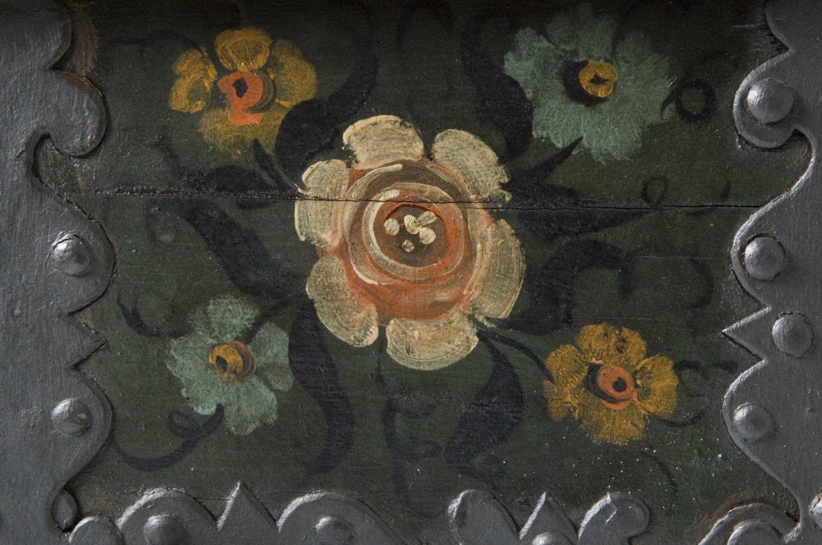 Kiste med buet lokk og heldekkende rosemaling, hvorav mye er senere tilføyelser eller restaureringer. Kulebena er også sekundære.