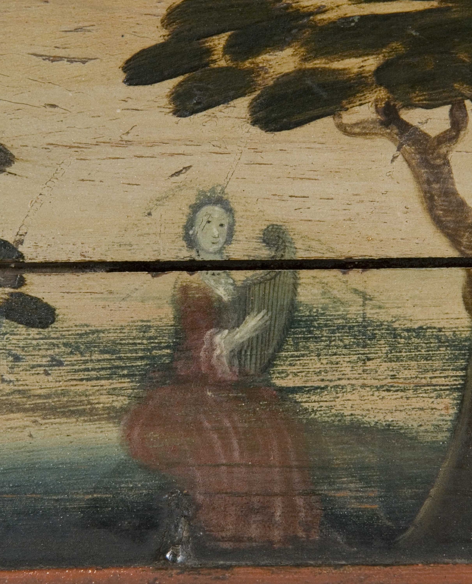 Flatskap med doble dører og klaff i overkant, hengslet på undersiden. Dekormalt med landskapsmotiver i feltene.