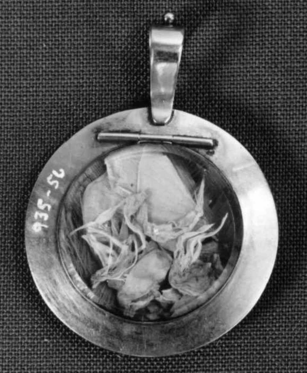 Medaljong med flettet hår og tørkede blomster inni.