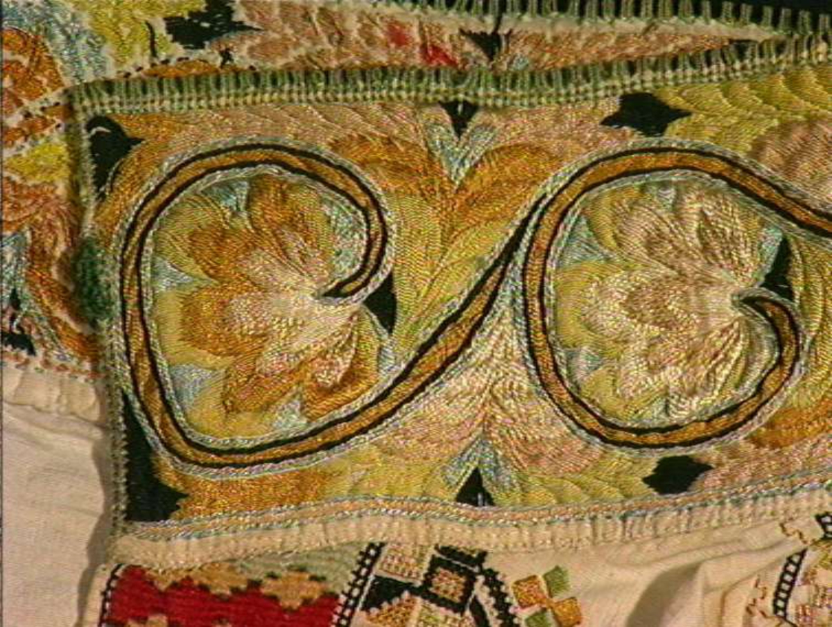 Skjorte fra Sauland, Hjartdal. Broderi på bolen uttrekksøm, klostersøm og korssting. Halslinning og slengerm sydd i plattsøm 
Halskvarde (halslinning) mål:  7,7cm.x57cm ca. Broderi 6,8cm.
Broderi på skulder ca 5,5x6,5cm. 
Brodert bord på slengerm 4cm., avslutning knapphullskant og attersting.