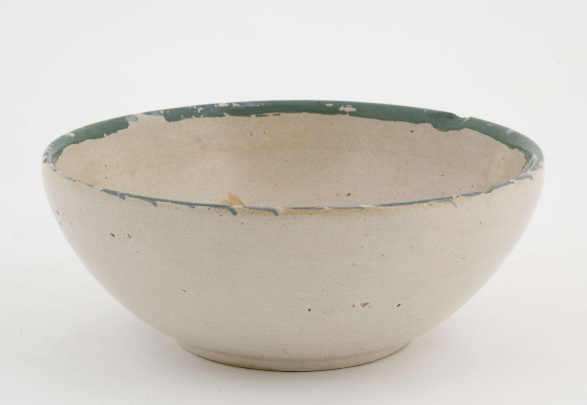 Beige keramikkbolle med flerfarget blomsterdekor i bunnen. 