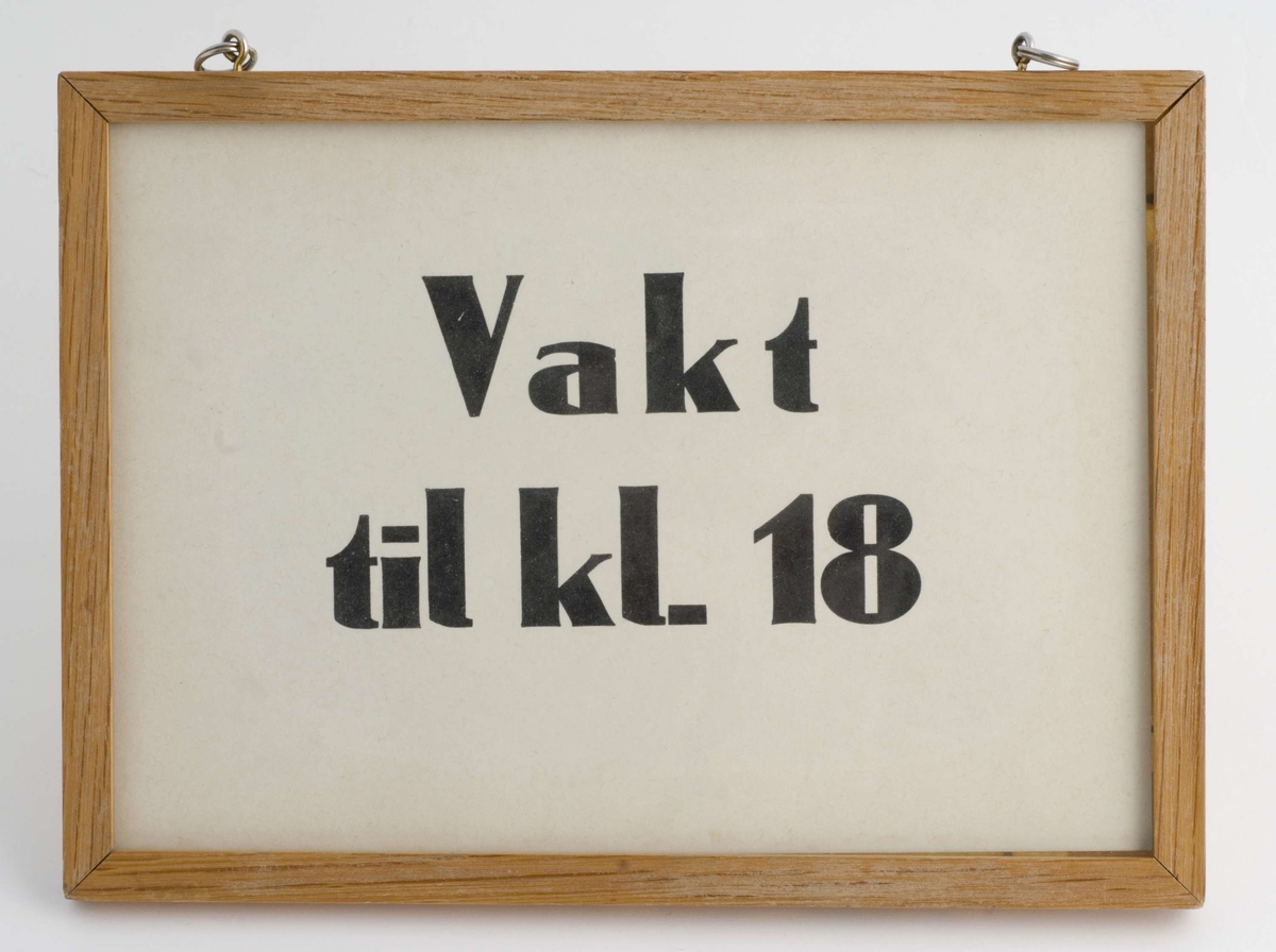 Svart trykk på hvit papp i lys treramme.