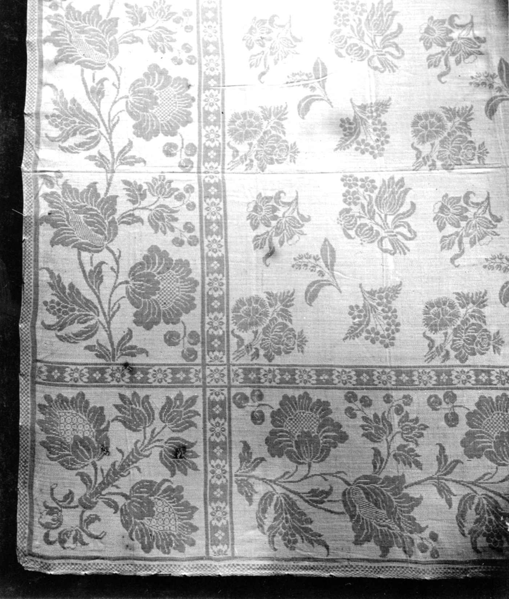Hvit damaskduk med mønster av strøblomster, blomsterrankebord. Antagelig fra Tyskland slutten av 1700-tallet.