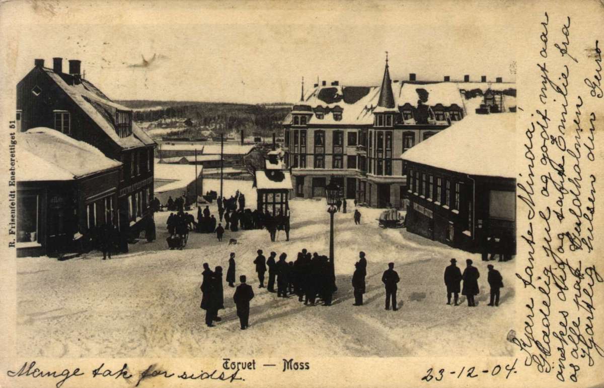 Postkort. Julehilsen. Mennesker står rundt på torget i Moss en vinterdag. Datert 23.12.1904.