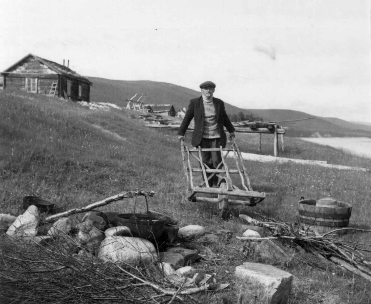 Mann med høytrillebår ved ildsted m. kokepinne (goanko), Javrebajnjarga, 1952.