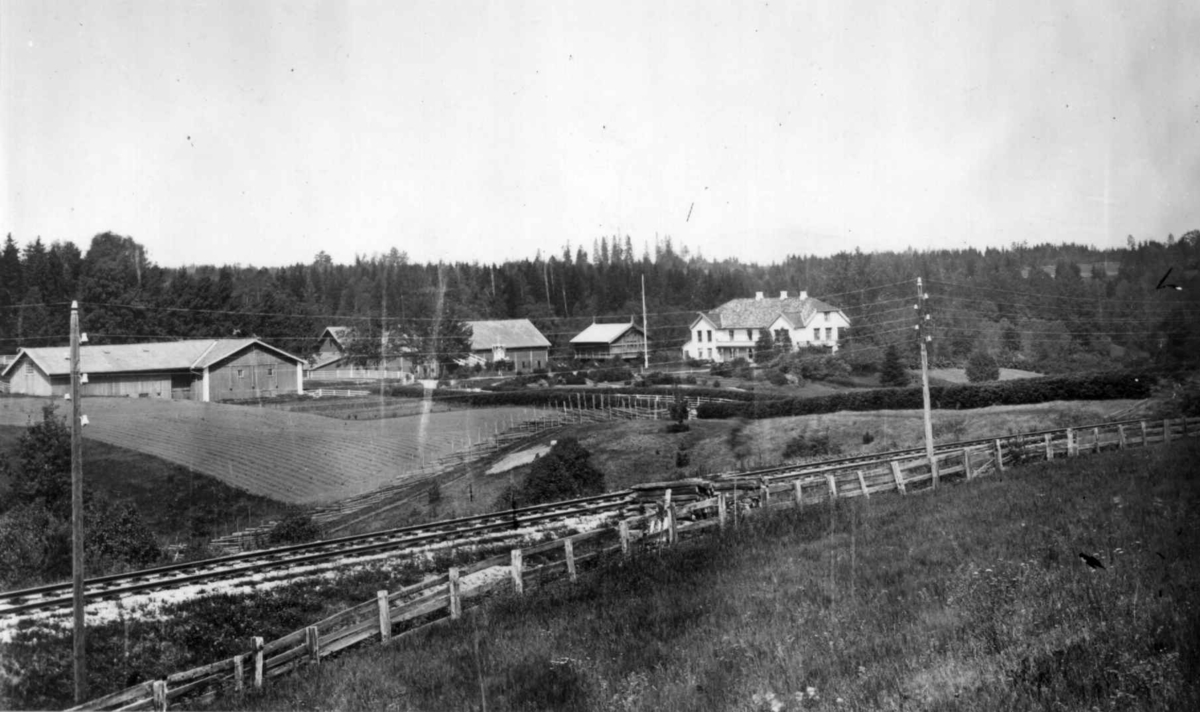 Dal gård, Ullensaker. Oversiktsbilde med gjerder og jernbanelinje i forgrunnen.
Fra serie fotografert av kammerherre Fredrik Emil Faye (1844-1903), gårdens eier.