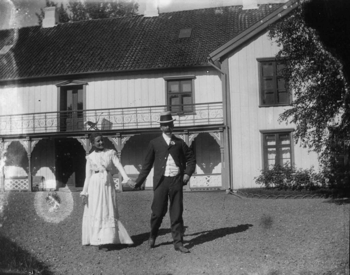 Dobbeltportrett, Selma Faye og Alfred Zimmer som forlovet på Dal, 1900. Paret poserer foran hovedbygningen.
Fra portrettserie av personer som bodde på eller besøkte Dal gård, Ullensaker, fotografert av gårdens eier, kammerherre Fredrik Emil Faye (1844-1903) i årene 1875-1900.