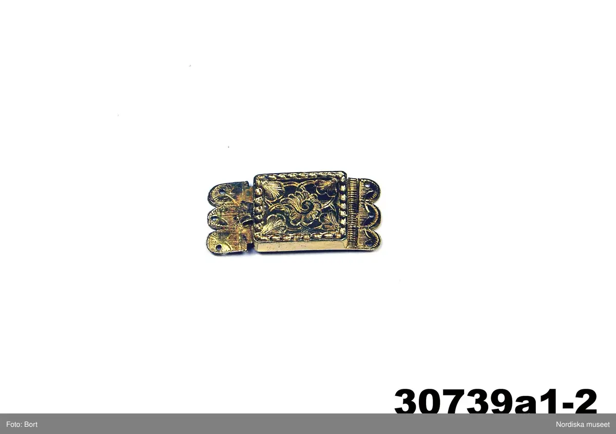 Huvudliggaren:
"a-e, Spännen. från Kalmar län. Af silfver.
Ink. gm friherre Emanuel Cederström [...]. 1/5 1881"

b) "Sölja, silfver, förgyld. H. 3,4 cm, Br 2,5 cm. Stämpel saknas. Frånsidan oförgyld."
c) "Sölja, Silfver, förgyld, gjuten. H 3,6 cm, Br 2,6 cm. Stämpel saknas. Frånsidan oförgyld."

A:1-2 Fyrkantigt halslås, helt förgyllt eller möjligen av mässing, graverad dekor i 1700-talsstil med punsad kant. Fäste för 3 kedjor som alla saknas.
/Berit Eldvik 2007-02-27 