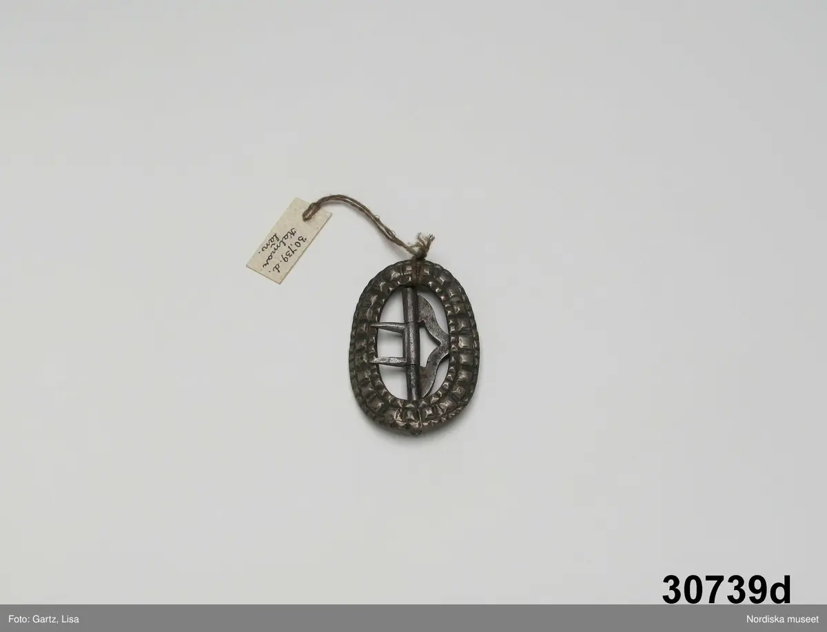 Huvudliggaren:
"a-e, Spännen. från Kalmar län. Af silfver.
Ink. gm friherre Emanuel Cederström [...]. 1/5 1881"

b) "Sölja, silfver, förgyld. H. 3,4 cm, Br 2,5 cm. Stämpel saknas. Frånsidan oförgyld."
c) "Sölja, Silfver, förgyld, gjuten. H 3,6 cm, Br 2,6 cm. Stämpel saknas. Frånsidan oförgyld."

A:1-2 Fyrkantigt halslås, helt förgyllt eller möjligen av mässing, graverad dekor i 1700-talsstil med punsad kant. Fäste för 3 kedjor som alla saknas.
/Berit Eldvik 2007-02-27 