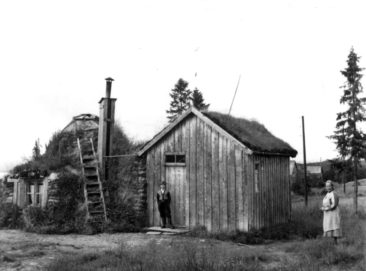 Oskar Jåmas vintergamme med vintergang. Utefor står Algot Peder Jåma og en kvinne, Limingen 1956. 