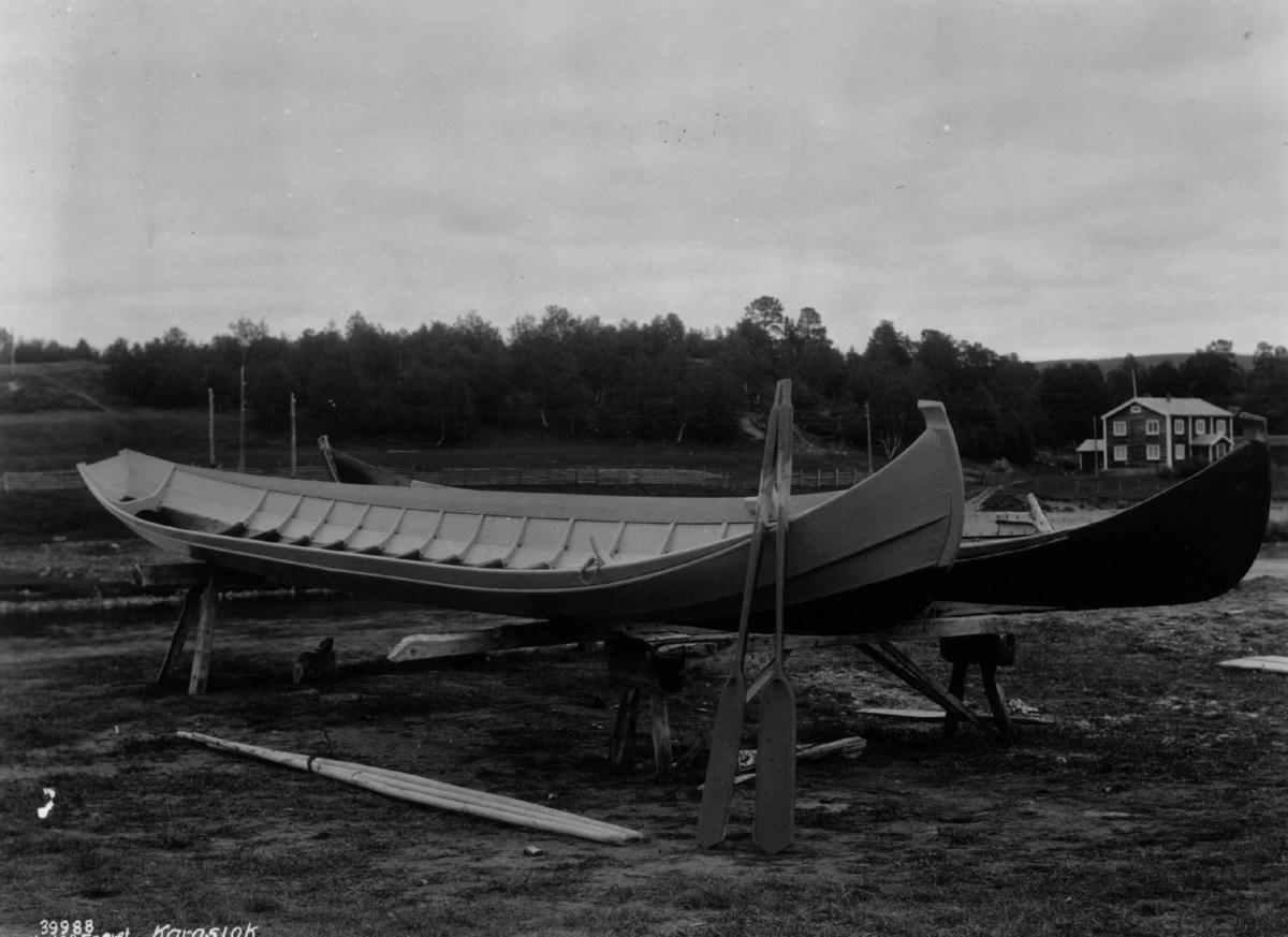 Båter. To nyoverhalte elvebåter på land. I bakgrunnen en bolig. Karasjok 1933.