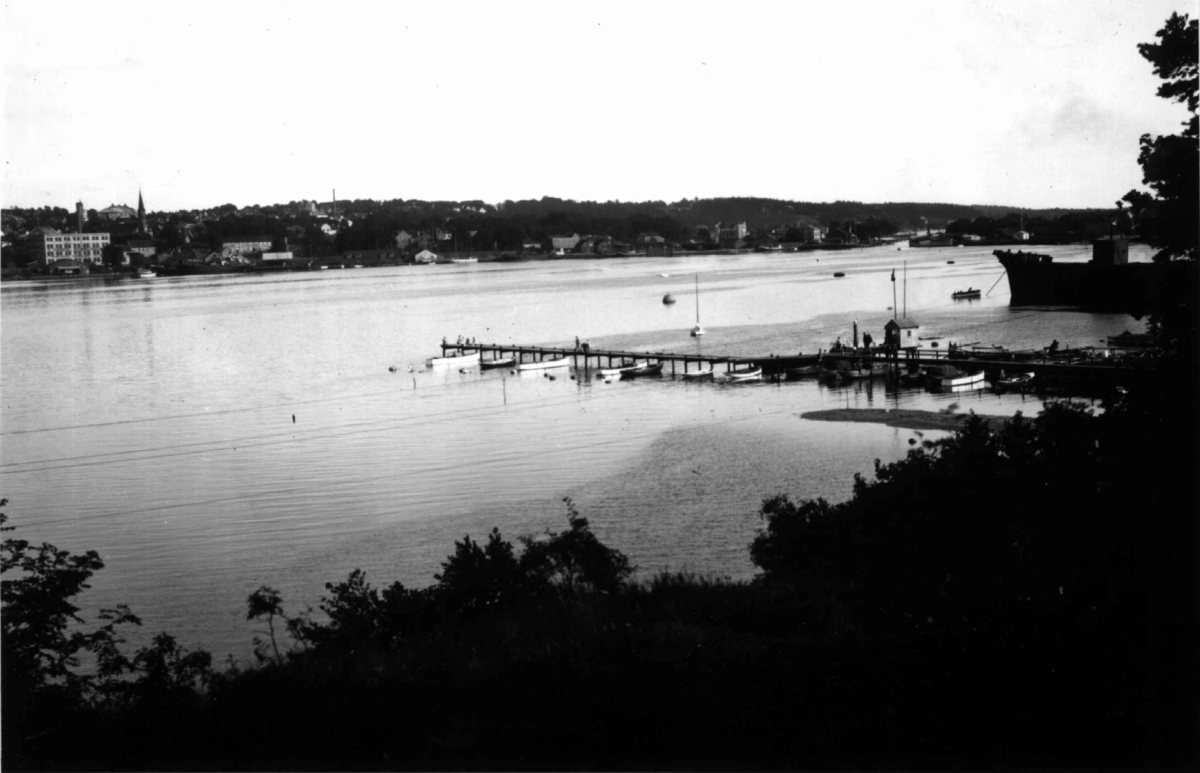 Moss, Østfold. 1930. Oversiktsbilde over Mossesundet. Brygger med båter. Bebyggelse i bakgrunnen.